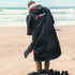 Gul EVORobe Hooded Changing Robe Black | Surfer changing on the beach