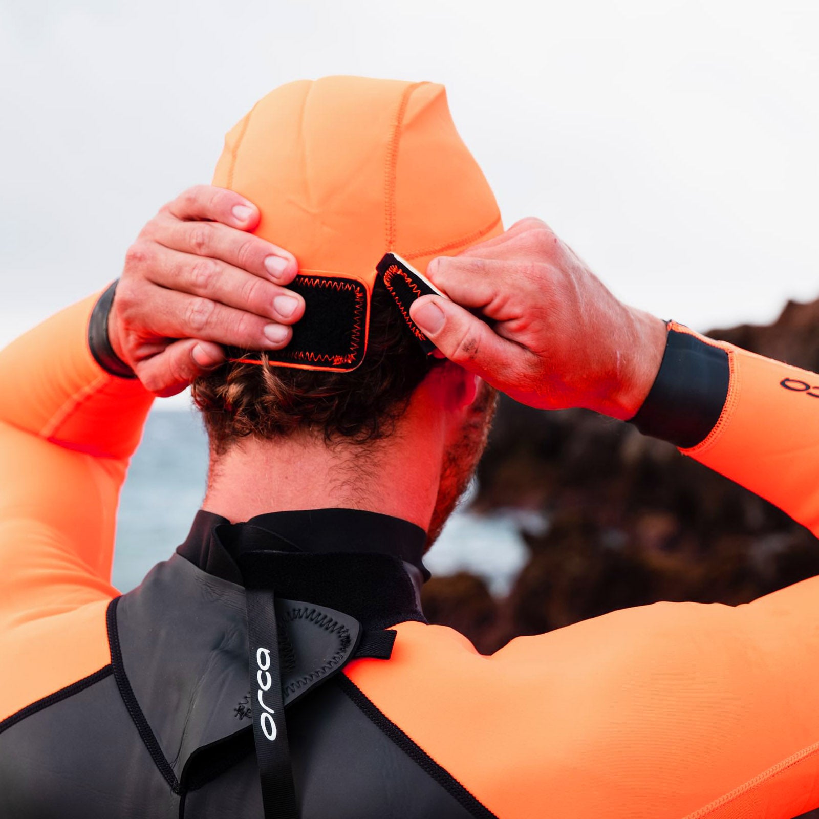 Orca Orange Neoprene Swim Hat in use showing adjustable fastening